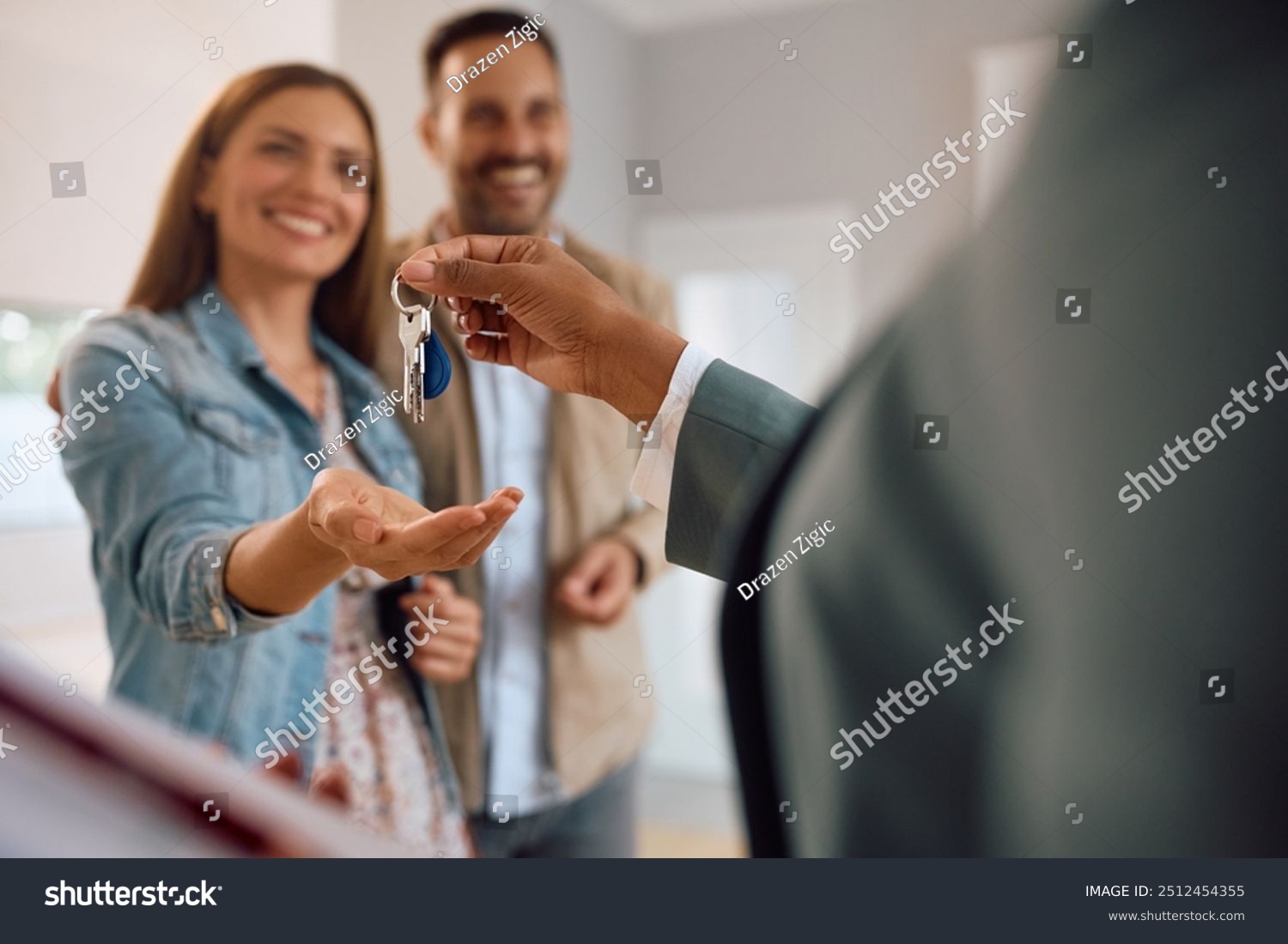 stock-photo-close-up-of-happy-couple-receiving-keys-of-their-new-home-from-real-estate-agent-2512454355